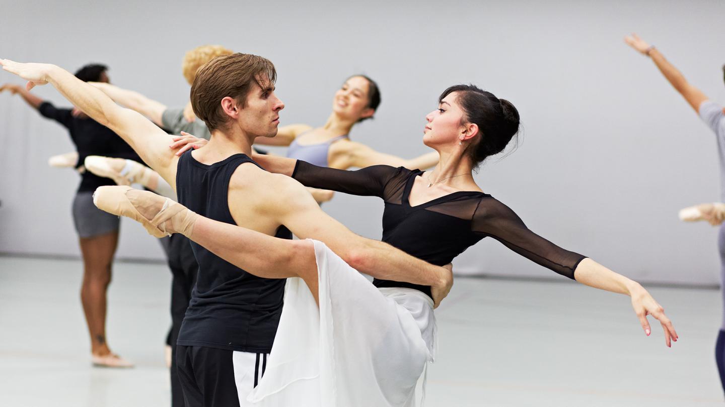 Dancers hold each other with one arm stretched behind them