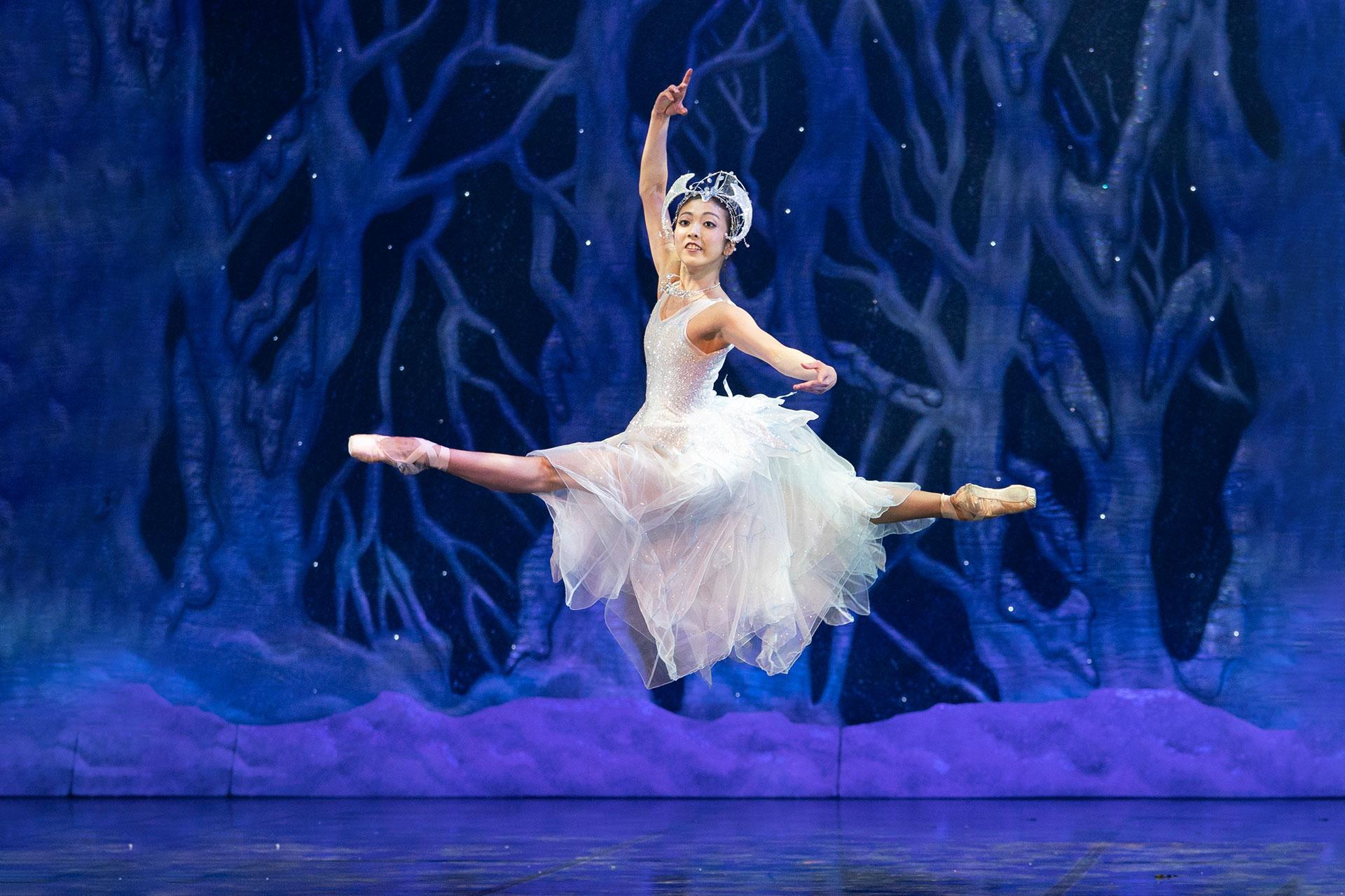 Ayami Miyata in a sparkline whide snowflake dress leaps in a grand jeté