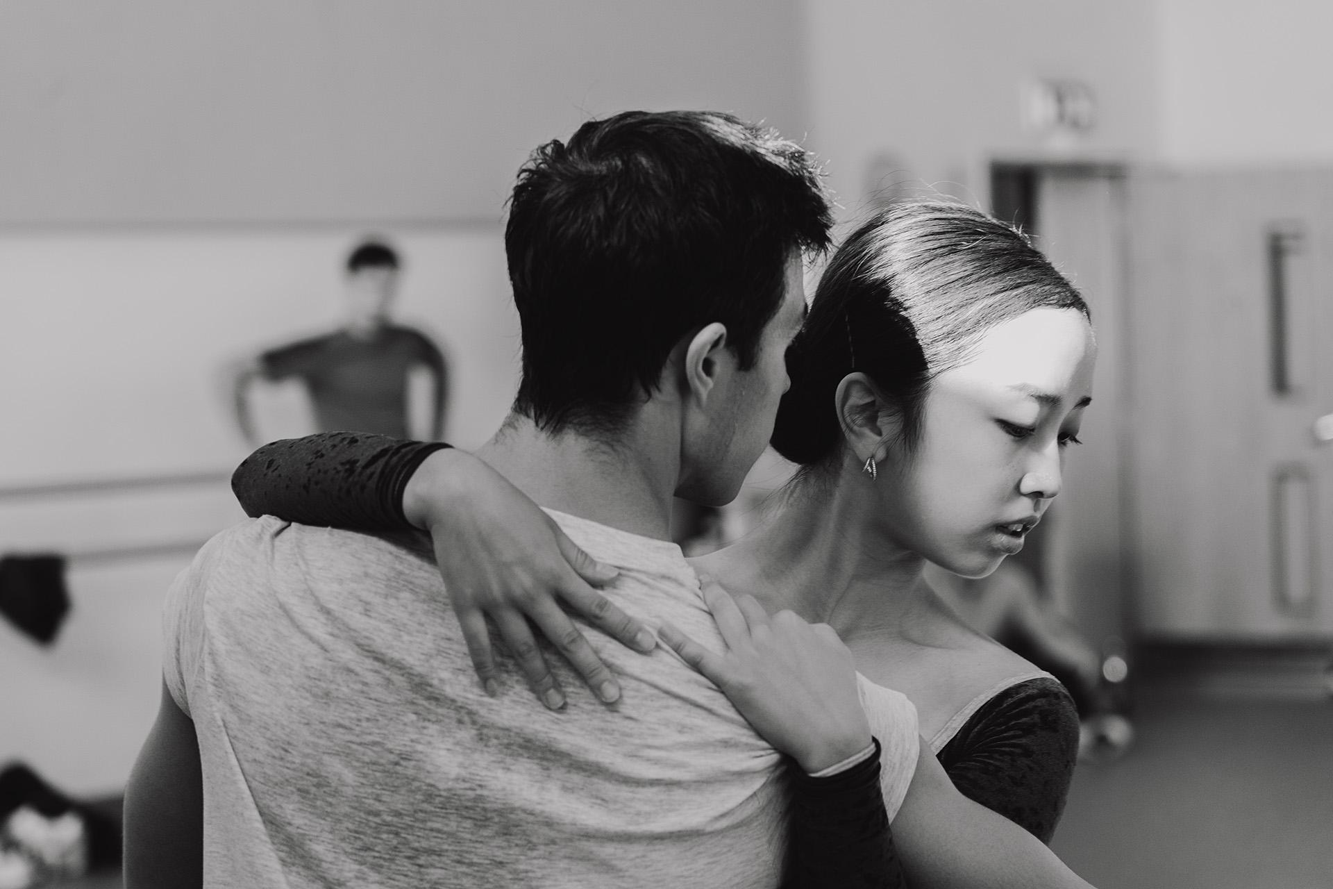 Monochrome image of two dancers, one looking away from the other while holding them tightly