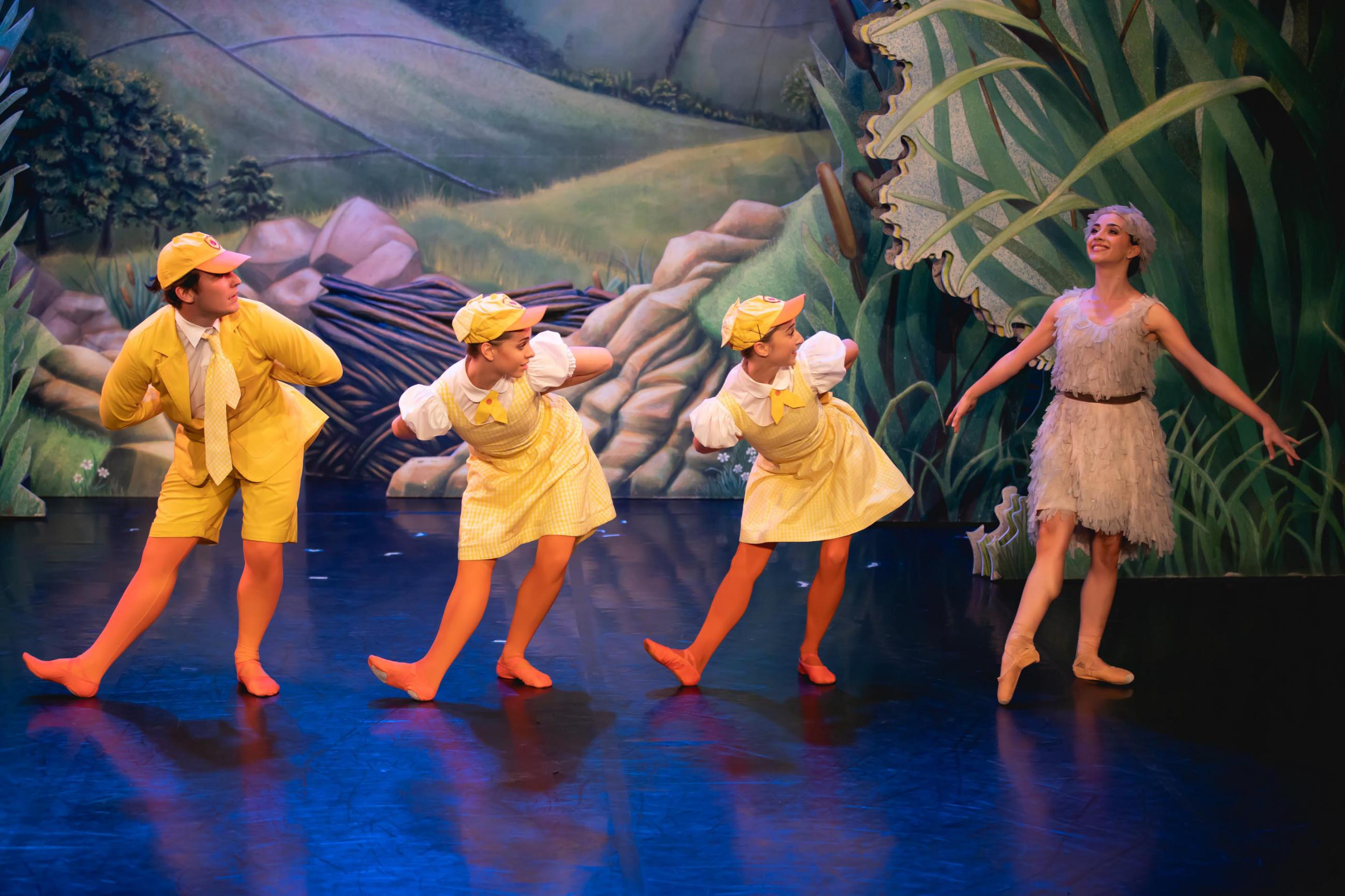 Four dancers dressed as ducklings in a line