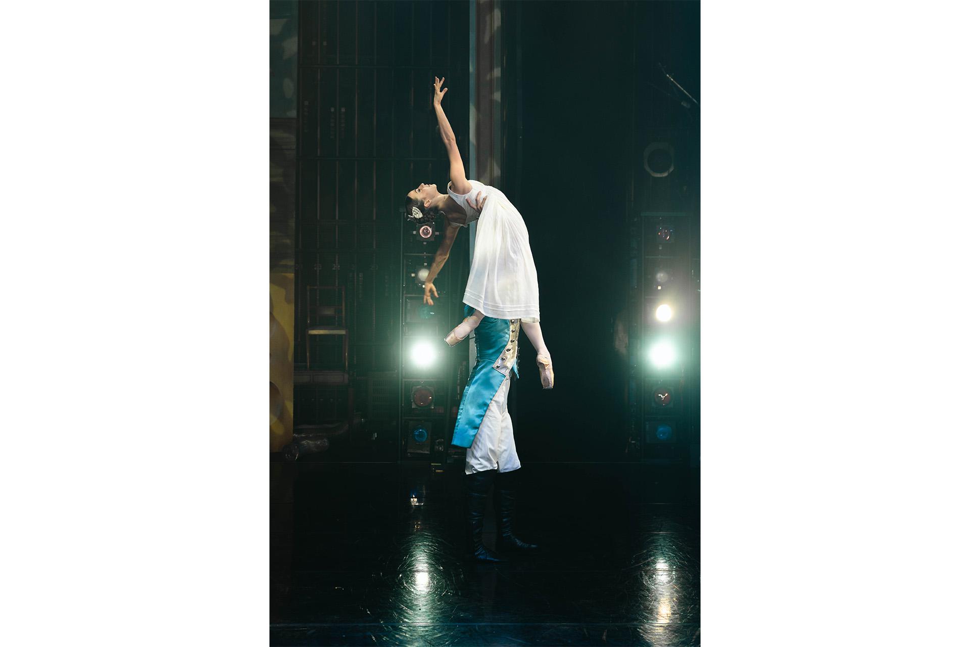Dancer dressed as a soldier hold up a dancer in a white dress with one full extended arm