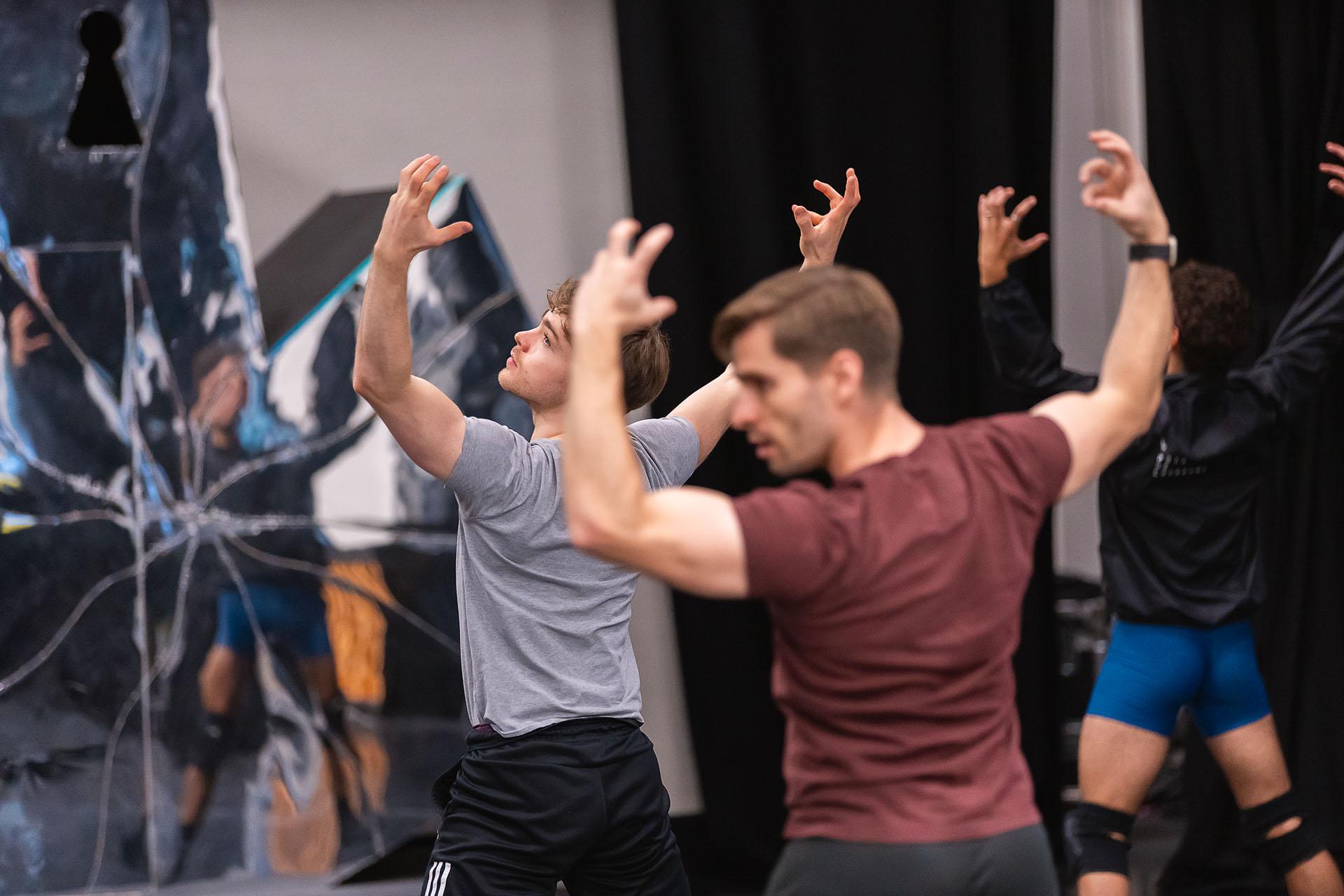 Male dancer holds his arms up as the Beast as he rehearses the role