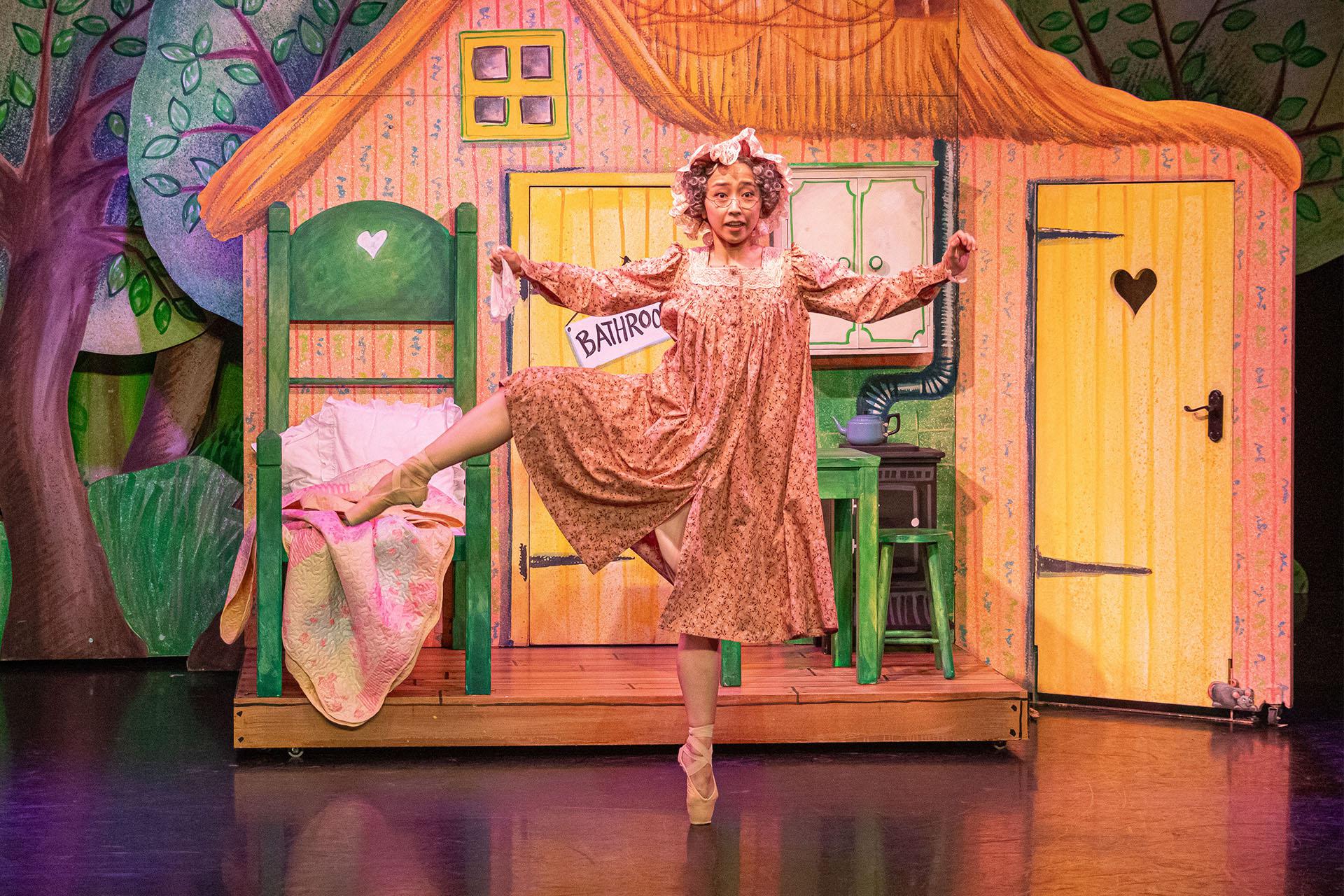 Little Red's grand-mother dancers in her home wearing an old-fashioned night-hat over her grey, curly hair