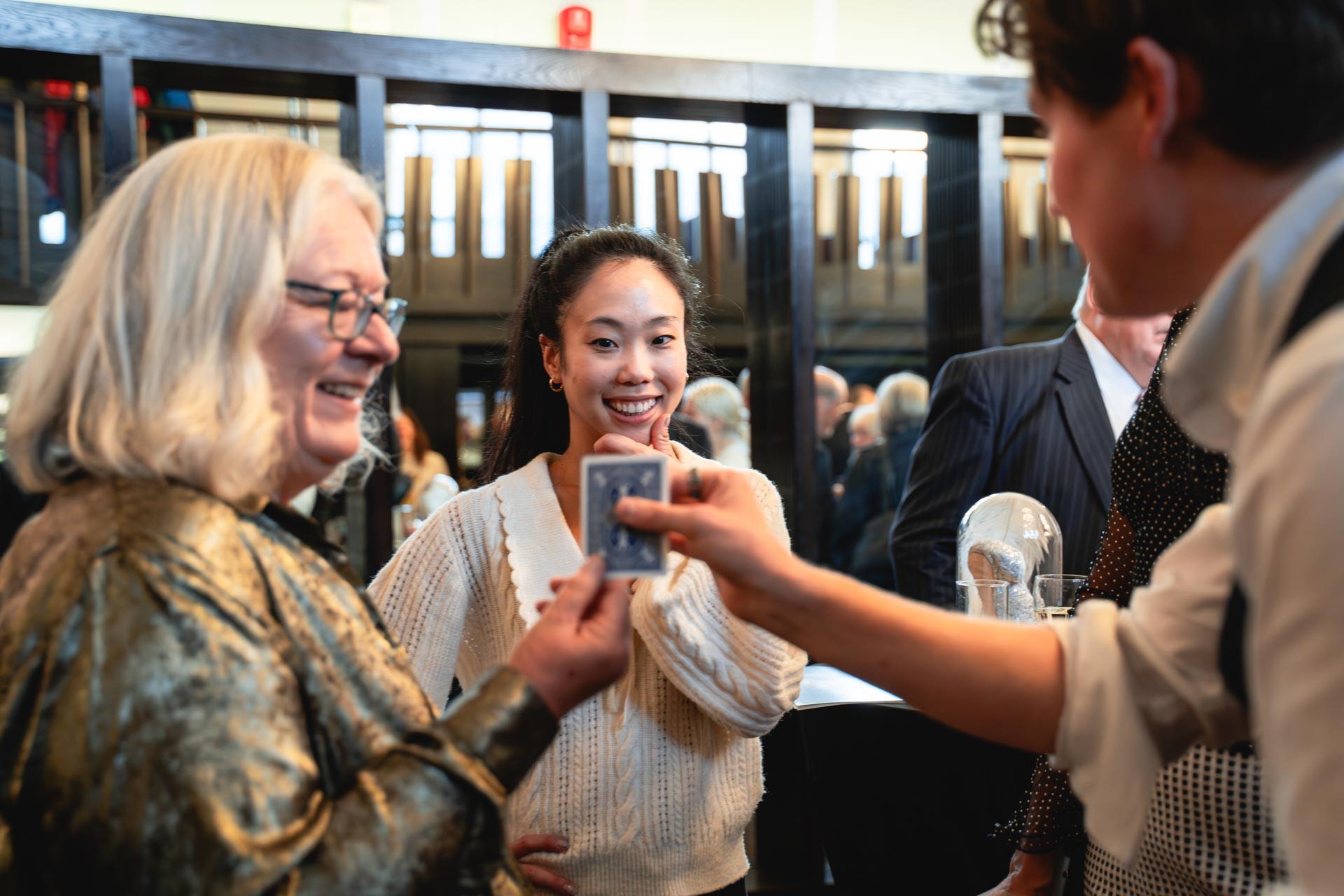 Two people react with surprise as a magician shows them a card