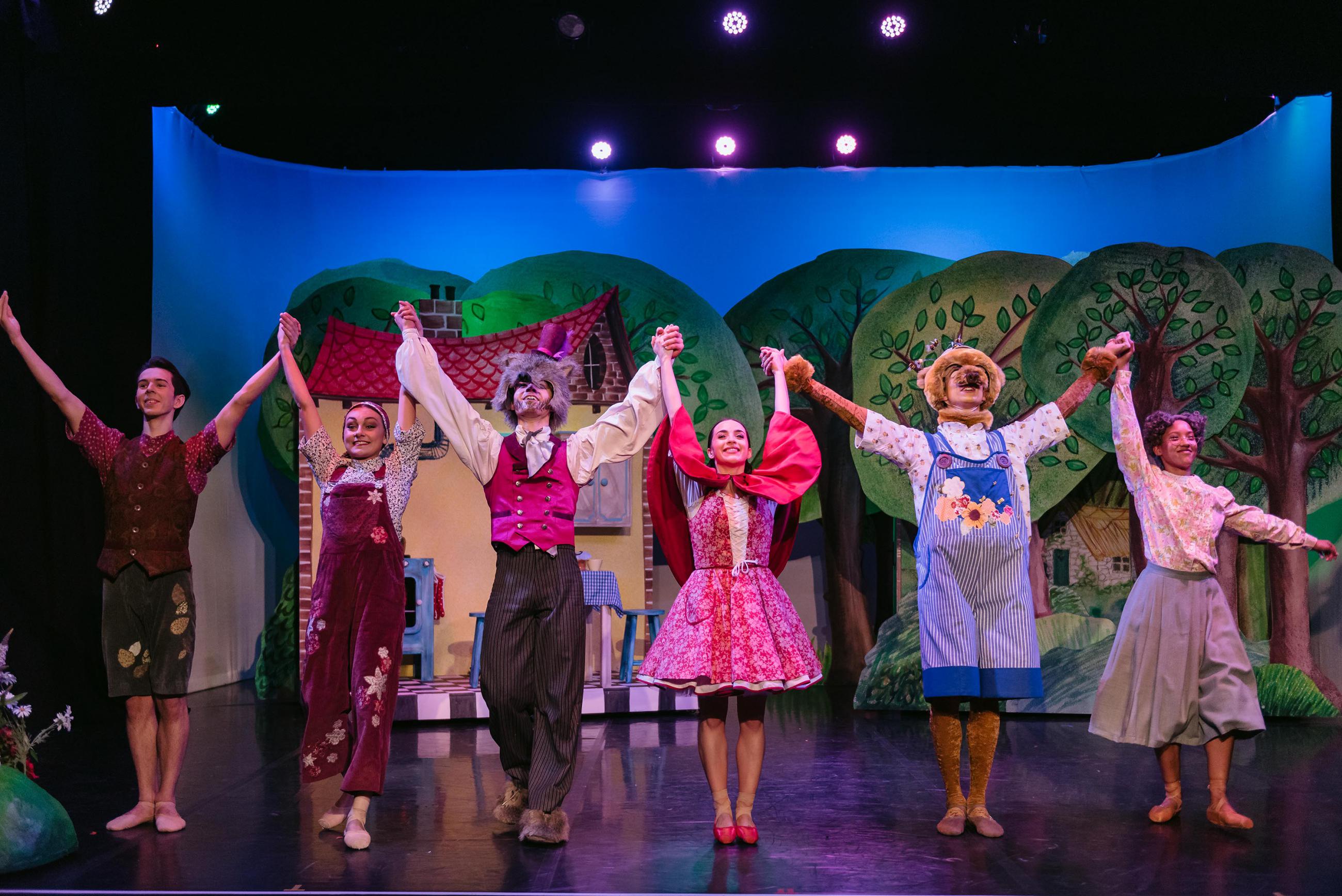 Six dancers in costume of Little Red Riding Hood taking a bow