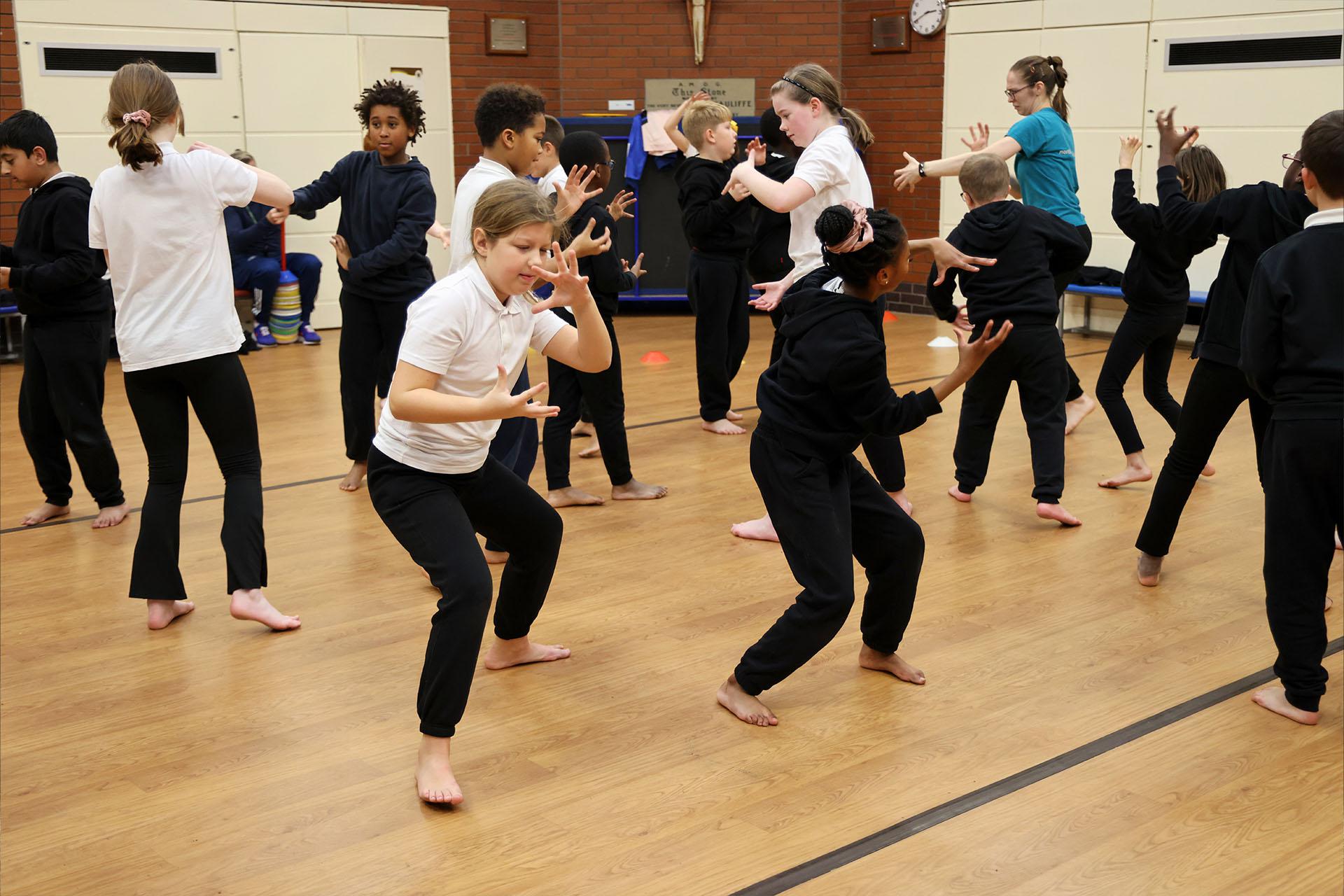 School children all dancing on a school hall floor, barefoot