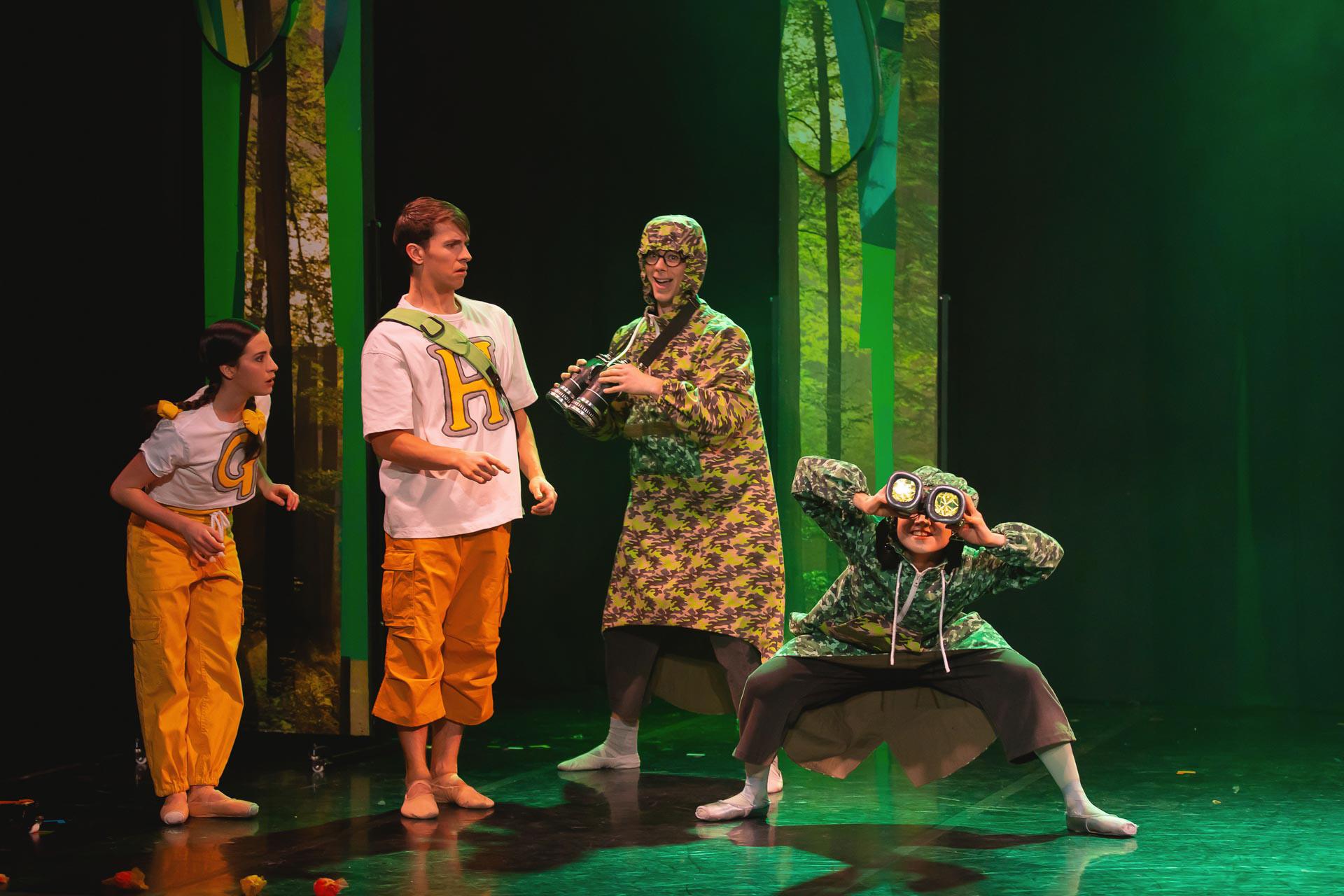 Four dancers on stage, two look very confused as the others look for birds through big binoculars.