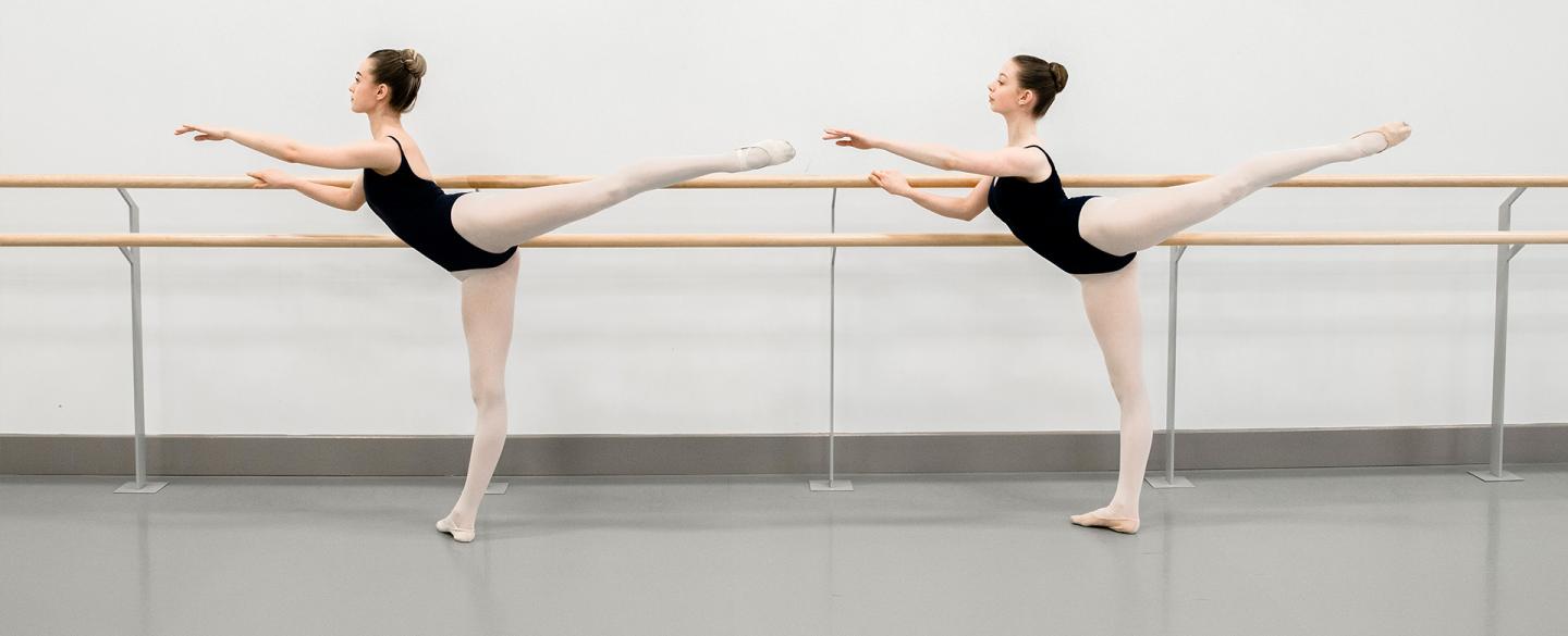 Two dancers posing at a barre