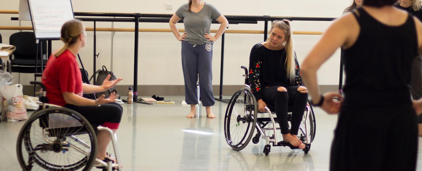 A group of people in a dance workshop, including two wheelchair users