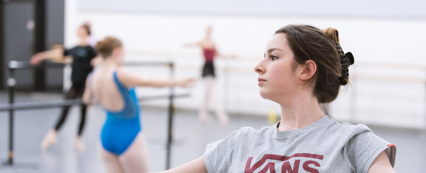 A young woman leaning backwards on a ballet barre