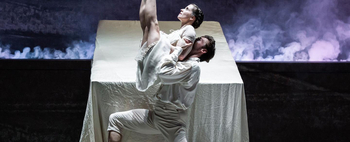 Dressed in their white night clothes and in front of their bad, Mr Rochester lifts Jane, her legs together and pointed at the sky