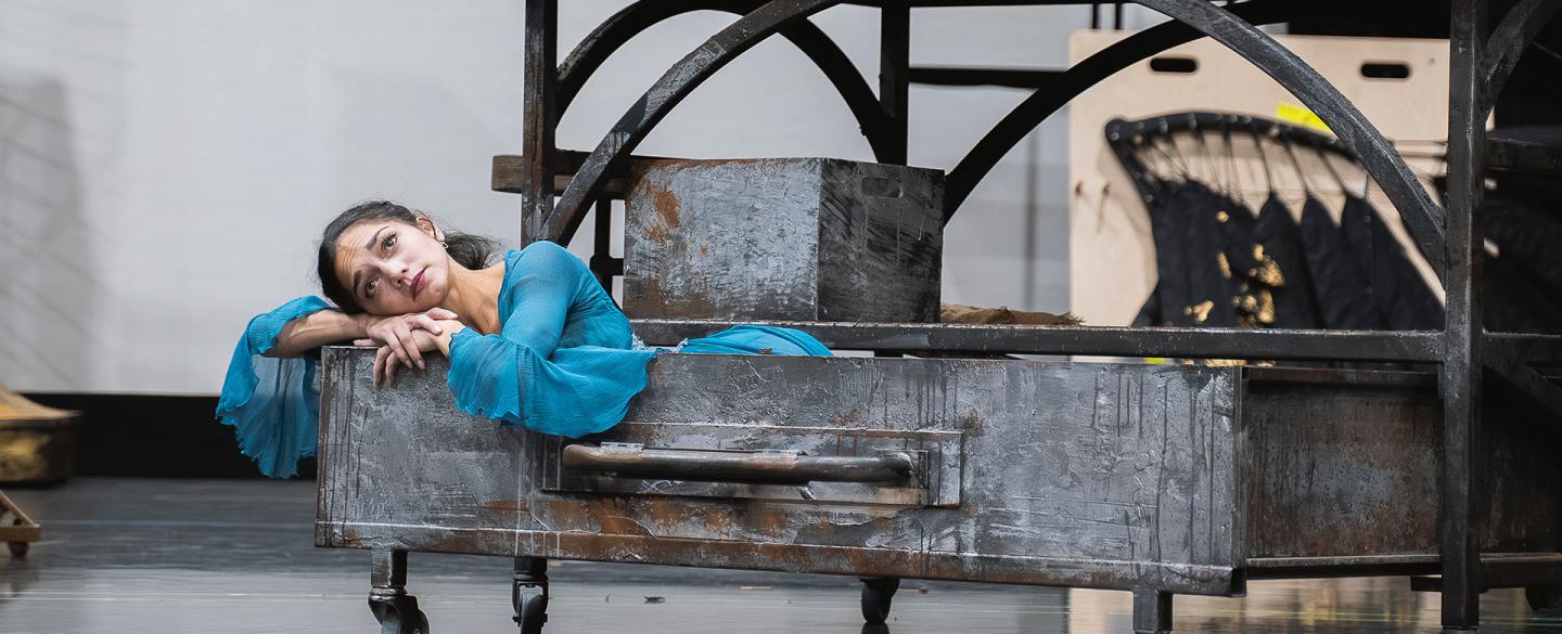 In an oversized drawer, a woman in blue leans over the edge and looks forlornly while resting her cheeks on her folded arms