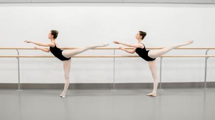Two dancers posing at a barre
