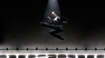 Kenneth Tindall mid-jump holding an old-fashioned microphone in the poster image for I Got Rhythm taken by Jason Tozer