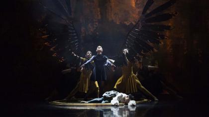 Morgan stands proudly with her new black wings unfurled while Merlin lies drained at her feet