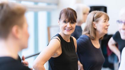 A woman stood relaxing by a ballet barre smiling