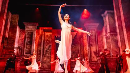 Juliet dressed in a white shift ands en pointe against a dramatically lit set