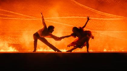 Silhouetted by bright, blazing orange, Rochester and Bertha at the same time pull away and hold on to each other