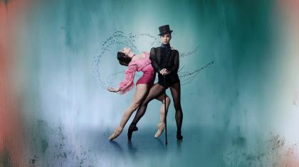 Wearing a black top hat and pointe shoes, the character of Gentleman Jack looks directly at the camera hands on a cane, a woman in pink hold onto her and leans back suggestively