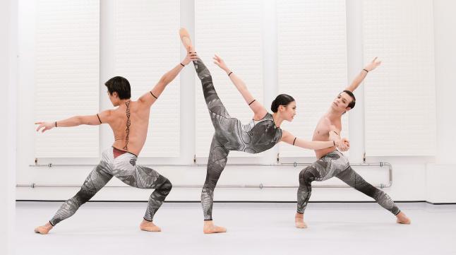 Three dancers stood with limbs outstretched against a white background